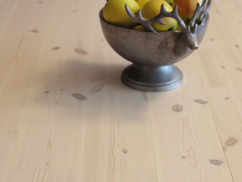 Grå metallskål med reinsdyrhoder, fylt med grønne pærer og en appelsin på lyst trebord.