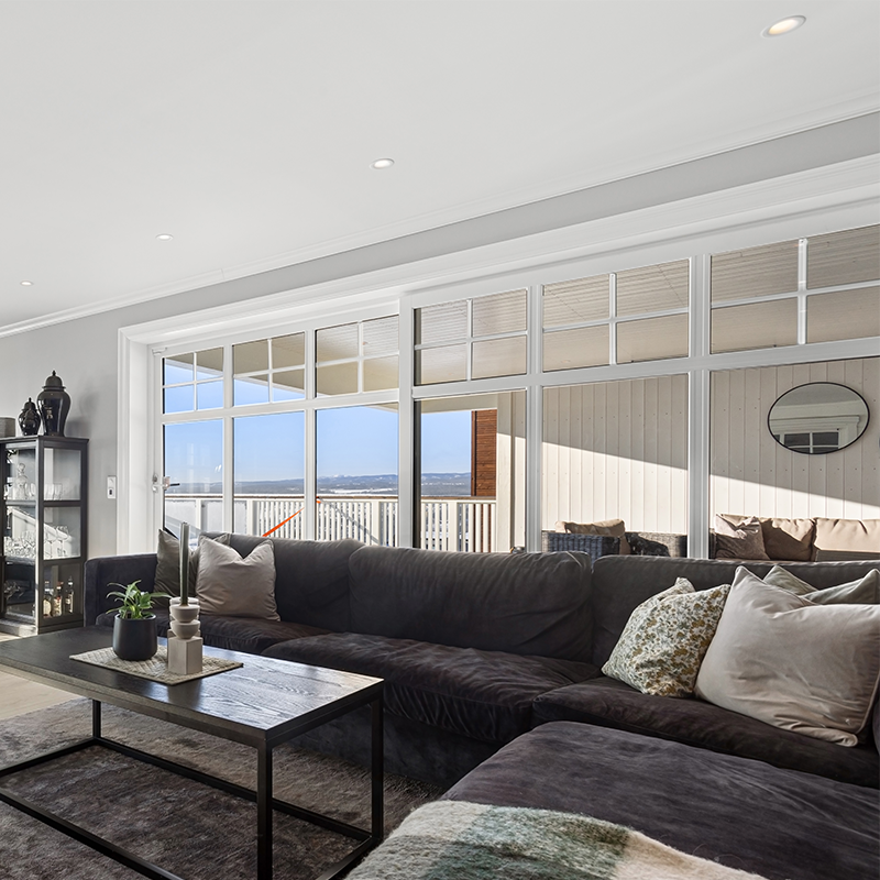 Stue med grå vegger, mørke møbler og store vinduer