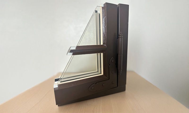 Brunt L-formet vindusprøvesnitt med to-lags glass på lyst trebord