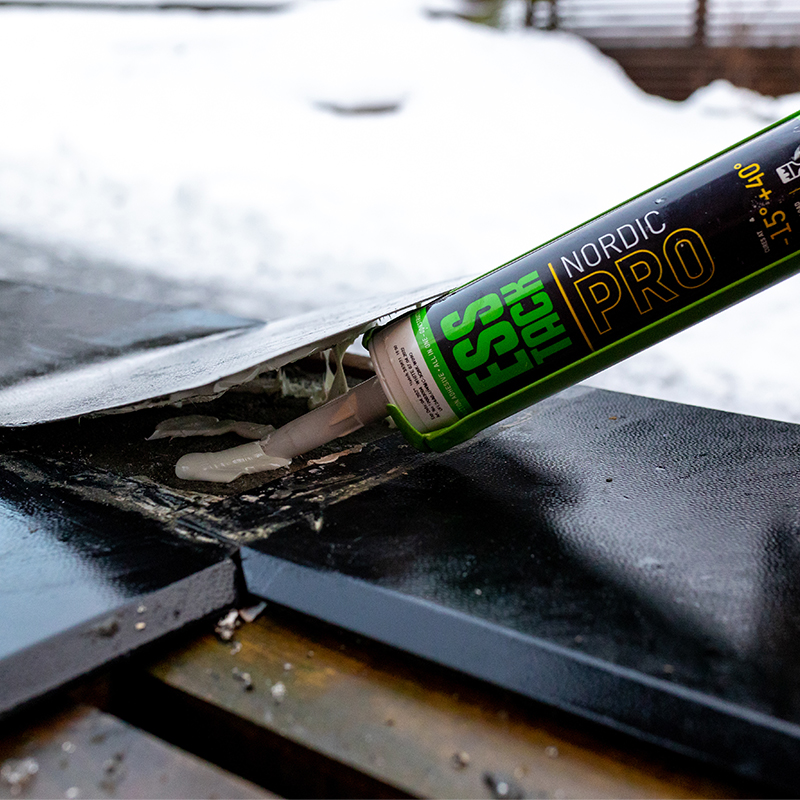 Grønt/svart ESS TACK Nordic PRO fugemasse sprøytes på svart takmembran med snø i bakgrunnen.