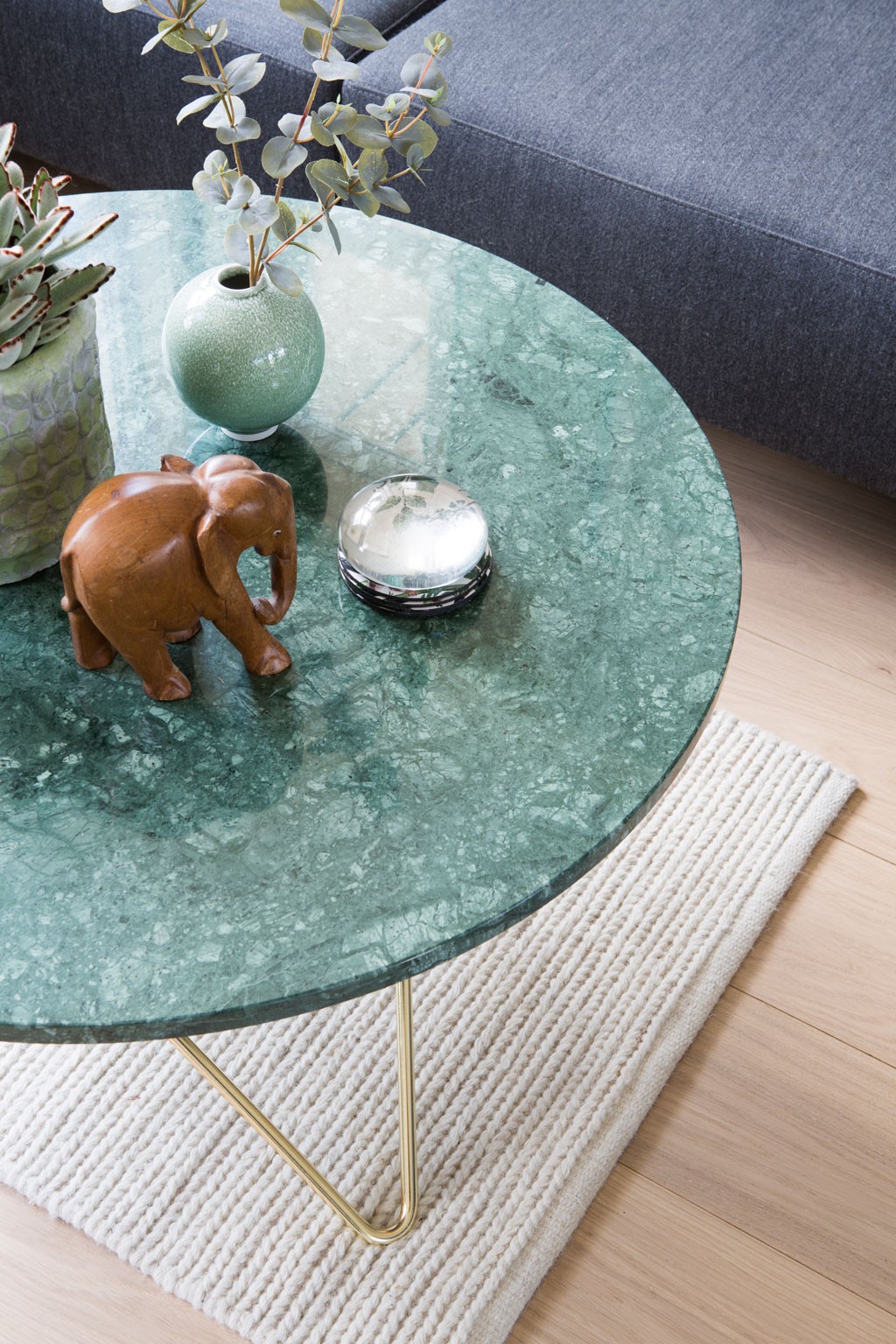 Sofabord av grønn marmor med gullben, grønn vase med eukalyptus, sukkulent, treelefant og sølvboks