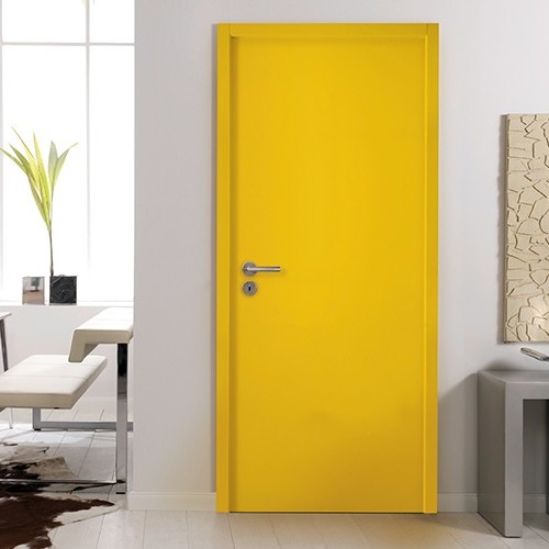 Gul dør i lyst, moderne rom med hvite møbler, abstrakt kunst og grønn plante.