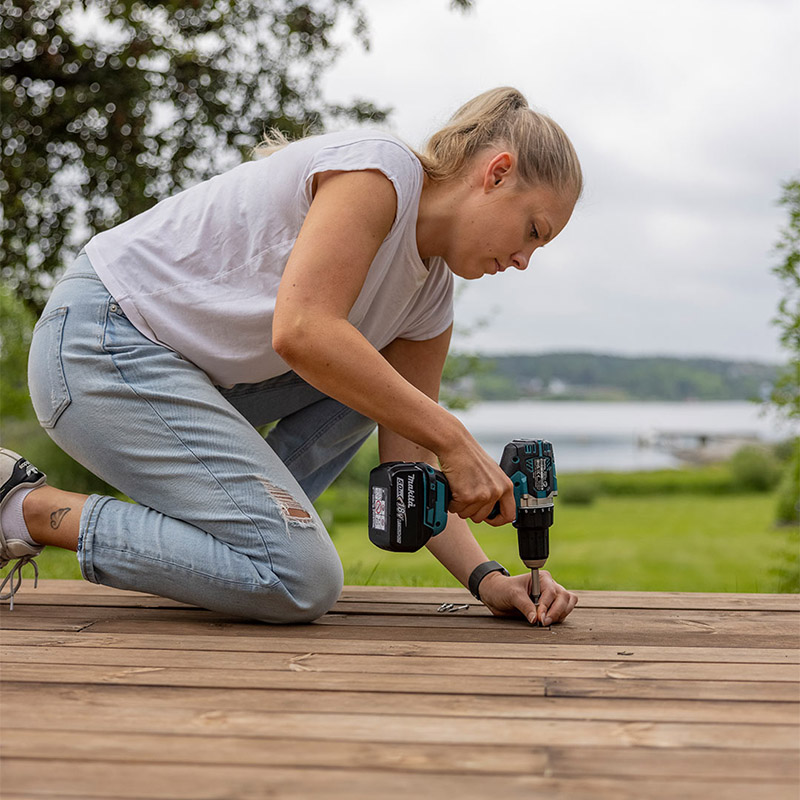 lite toppbile kvinne bruker drill for å skru i terrassebord