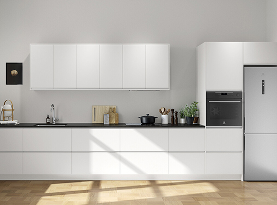 Minimalistisk, hvitt kjøkken med sort benkeplate, integrert ovn og kjøleskap, sollys på tregulv.