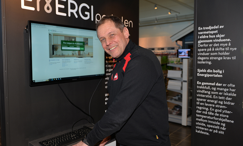 Person i svart jakke med røde detaljer foran skjerm som viser Energiportalens nettside på stand.