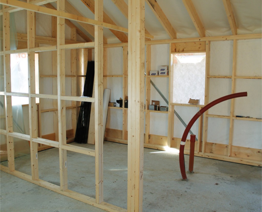 Uinnredet rom med lyse trestendere, hvite dukvegger og rødt fleksibelt rørstuss.