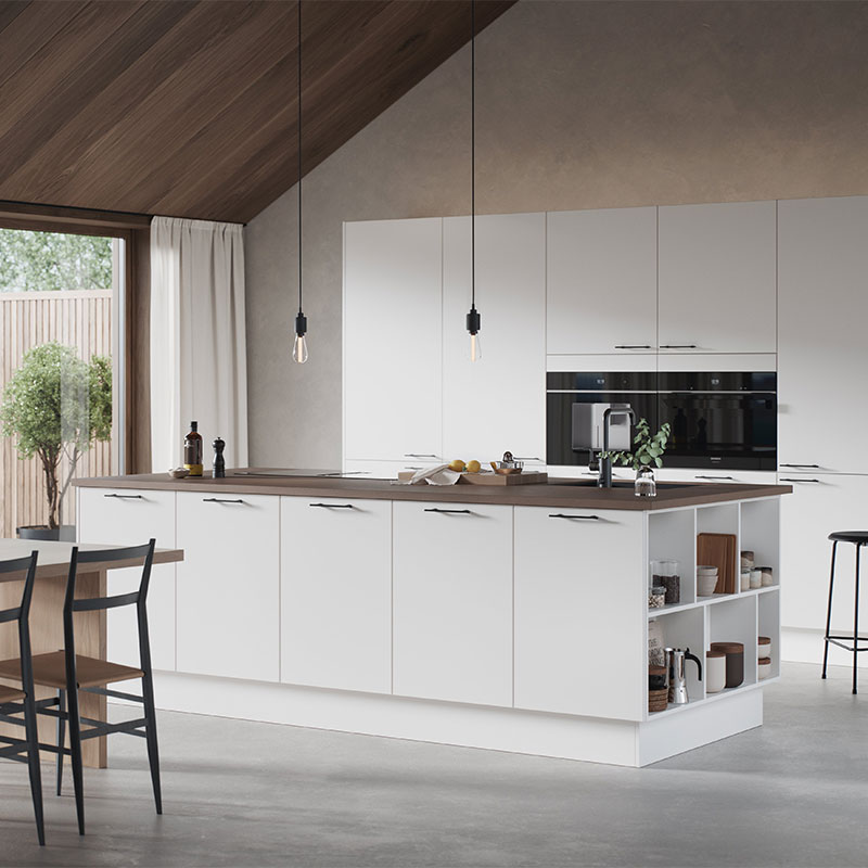 Moderne kjøkken med hvite skap, trebenkeplate, svart kran, hengende lyspærer og hageutsikt.