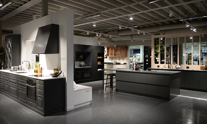 Moderne kjøkkenshowroom med svarte og hvite kjøkkenøy, barstol og blankt grått gulv