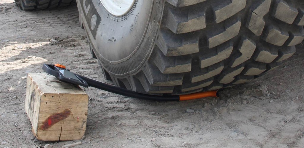 Kraftig grått lastehjul på støvete underlag, oransje-svart spade og trekloss