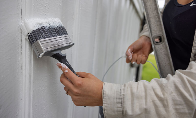 hus males utendørs med hvit maling og bred pensel