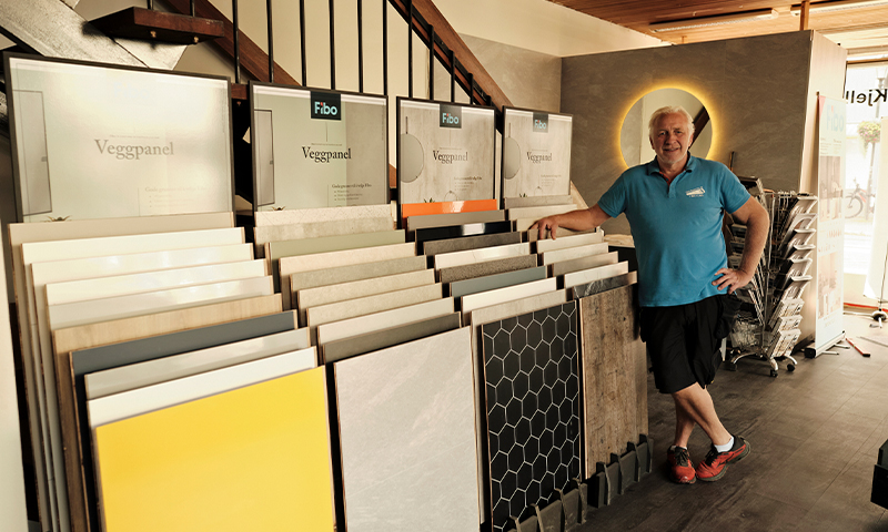 Butikkmedarbeider ved stativ med Fibo veggpaneler i gult, hvitt, grått, svart og mønstret