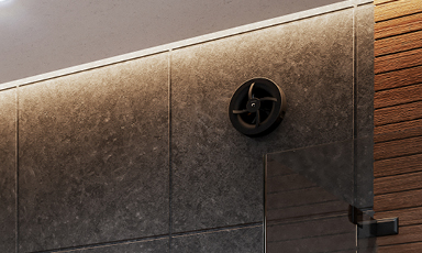 Badvegg med mørkegrå fliser, LED-stripe, rund svart ventil, glassdør og trepanel.