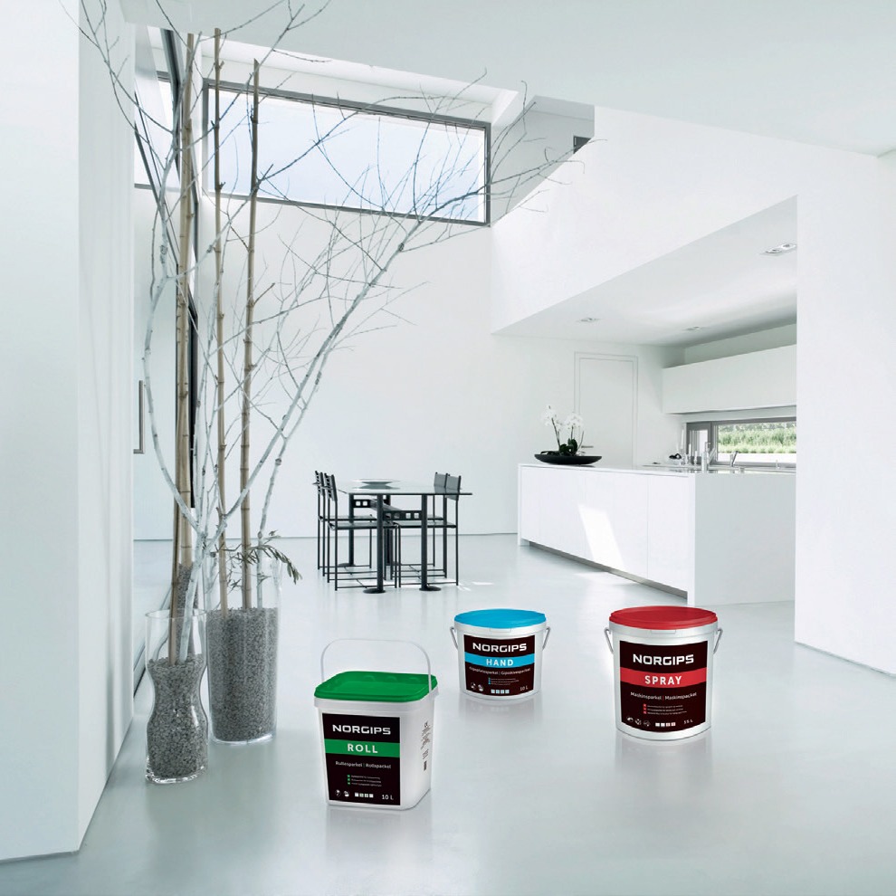 Moderne hvit stue med vaser med kvister og tre Norgips-bøtter med grønt, blått og rødt lokk.