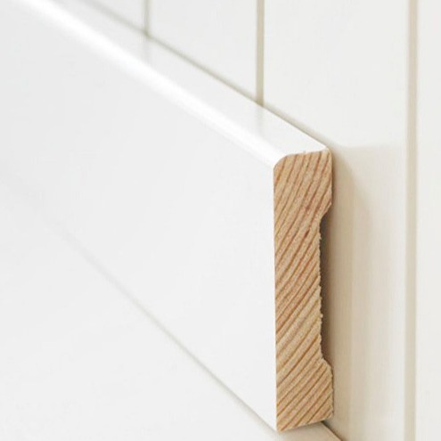 Hvit gulvlist med synlig lys furukjerne montert mot hvit flisvegg