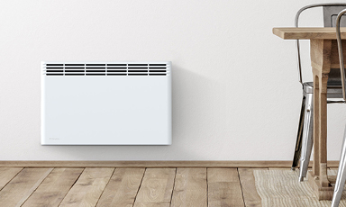 Hvit vegghengt panelovn på hvit vegg over lyst tregulv ved trebord og metallstol