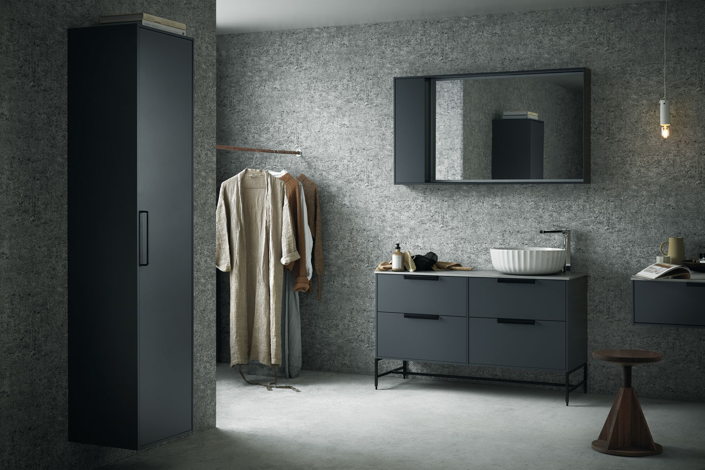 Minimalistisk grå baderom med sorte skap, rund hvit servant, hengende klær og trekrakk
