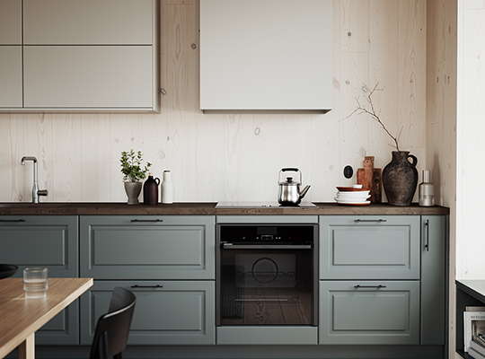 Moderne kjøkken med lyse trepanelvegger, salviegrønne underskap, hvite overskap og svart ovn.