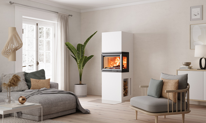 Moderne nordisk stue: hvit peis med ild, grå sofa, beige puter og grønn plante