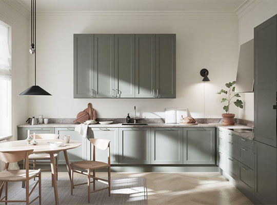 Lyse grågrønne kjøkkenskap i L-form, marmorbenk, rundt trebord, hengelampe og plante.