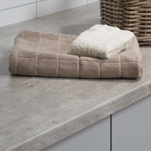 Beige rutet badehåndkle med lite hvitt håndkle oppå på grå benkeplate ved flettet kurv