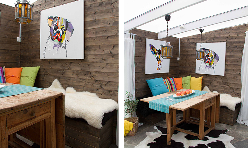 Innglasset koselig krok med mørke trepanel, rustikt trebord, fargerike puter, abstrakte hundebilder