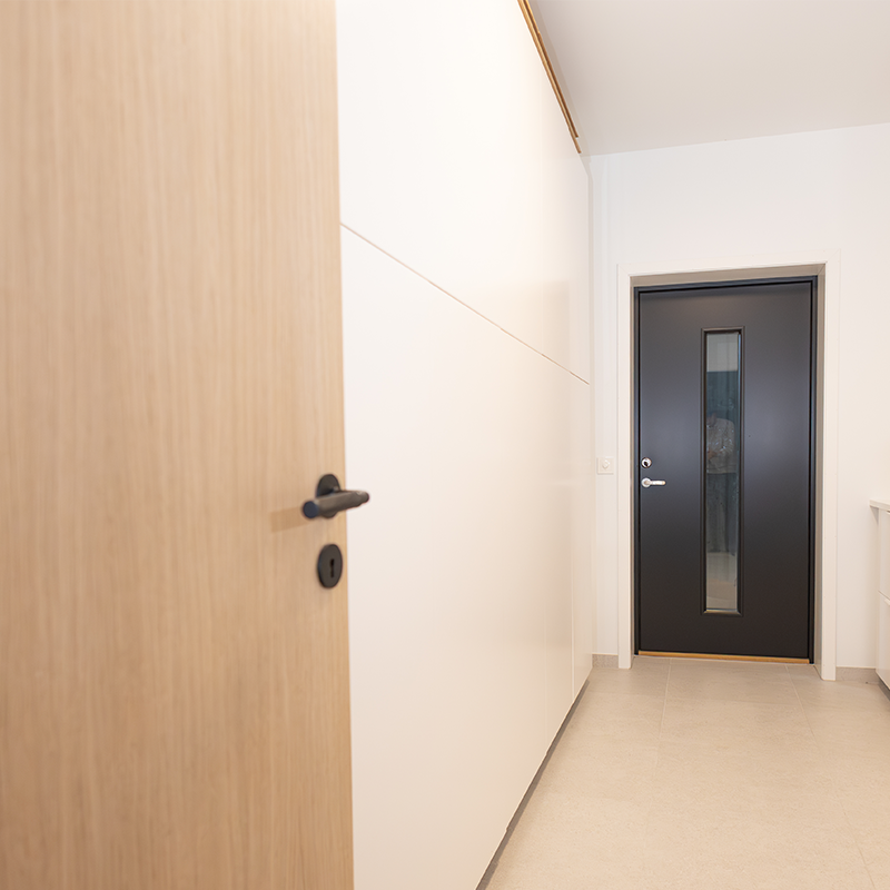 vaskerom med hvite vegger og sort dør med vindu i enden