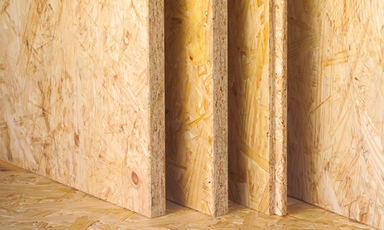 Fem gule OSB-plater lent mot gulv og vegg i samme trefibermateriale.