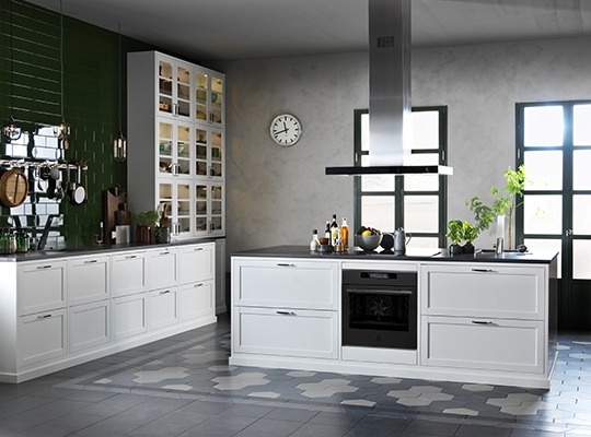 Lyst hvitt kjøkken med grønn flisvegg, grå heksagonfliser på gulv, ventilator og vinduer.