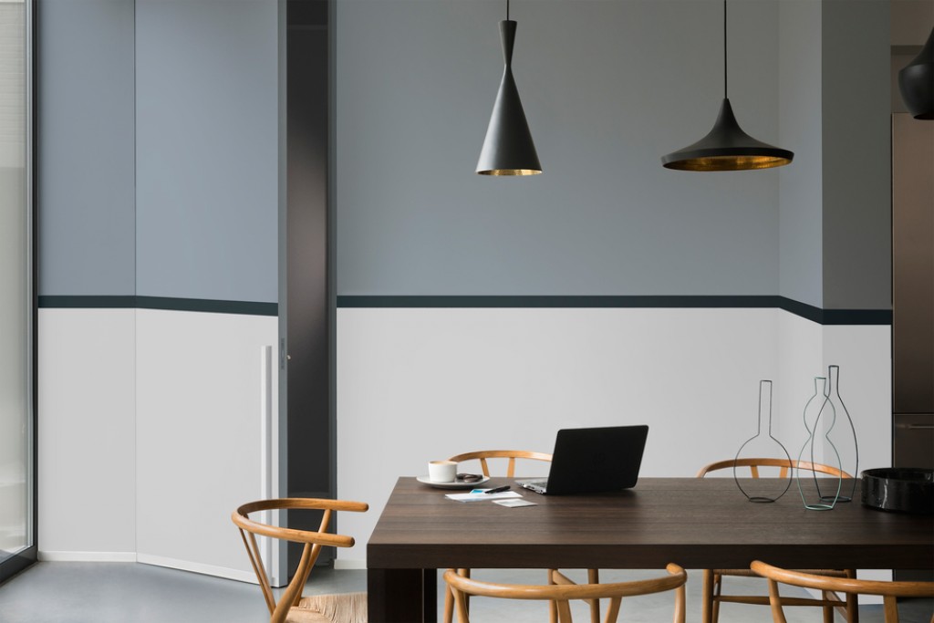 Moderne møterom med mørkt trebord, trestoler, svart laptop og hengende lamper mot grå-hvite vegger