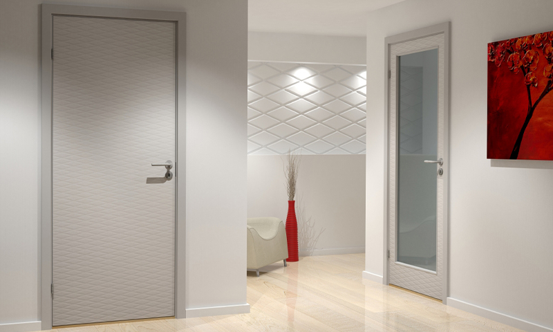 Hvit gang med to lyse dører (én glass), beige stol, høy rød vase og rødt maleri.