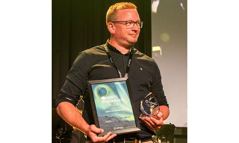 Person i svart skjorte på scenen med grønt diplom «Årets nykommer 2024» og gjennomsiktig trofé