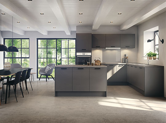 Åpent kjøkken med gråe skap og kjøkkenøy, store vinduer mot grønn hage, spisebord med sorte stoler.