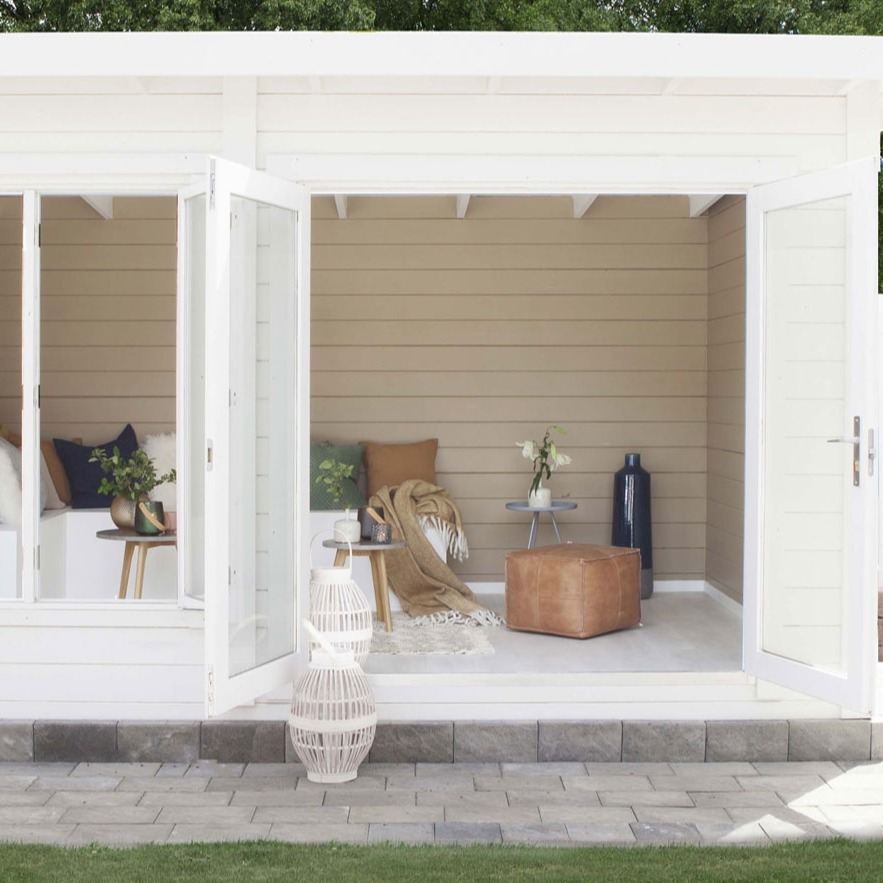 Åpent hvitt hagestue med beige vegger, grønne/brune puter, lærpuff, bord med planter.