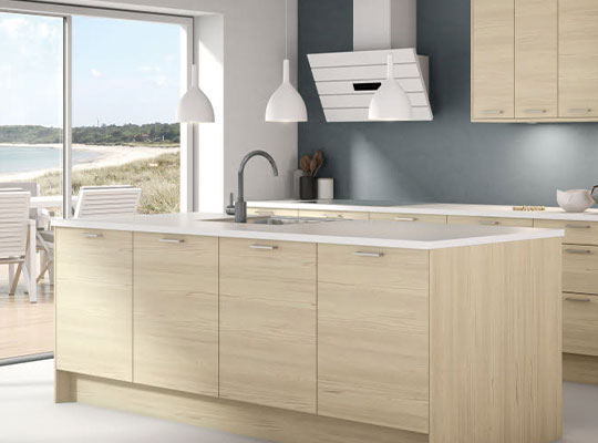 Moderne lyst trekjøkken med hvit øy og hengelamper, grå vegg og strandutsikt.