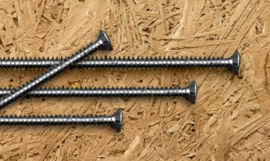 Skruer liggende oppå en sponplate