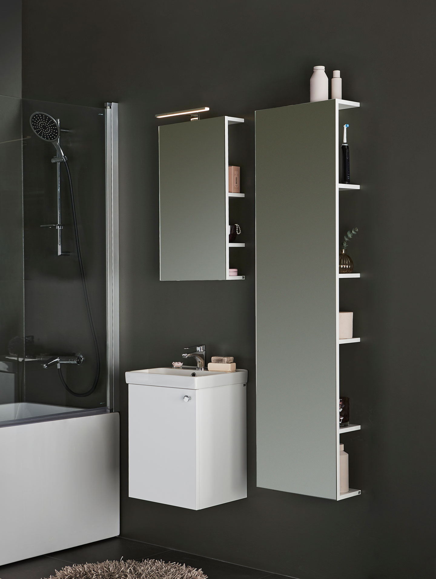 Mørk grønn vegg med hvitt servantskap, speilskap, høyt skap med åpne hyller og svart dusj