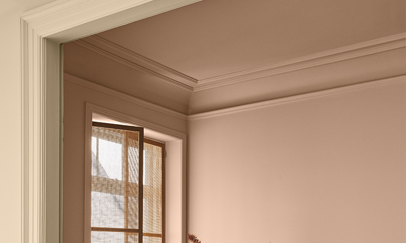 Tomt rom med beige vegger, hvit døråpning og vindu med lys, gjennomsiktig gardin.