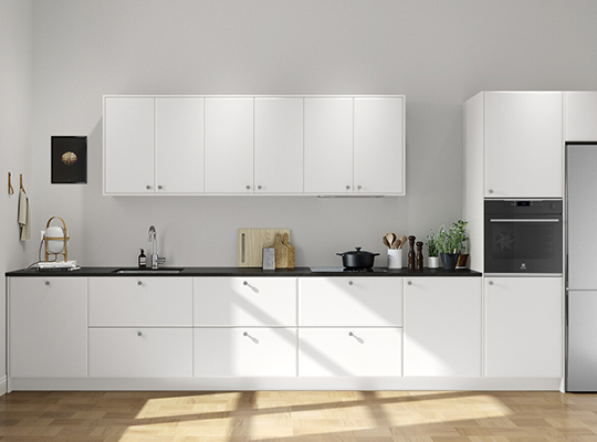 Moderne hvitt kjøkken med svarte benkeplate, tregulv, krydderurter og kjøkkenredskaper.