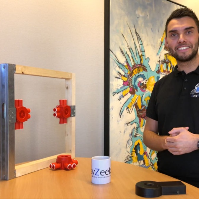 Treramme med røde koblinger, hvit easyZeek-kopp, svart enhet, fargerikt maleri i bakgrunnen.