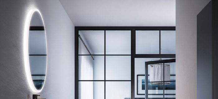 Moderne bad med hvite vegger, ovalt lysende speil og sort-framete glassdusj