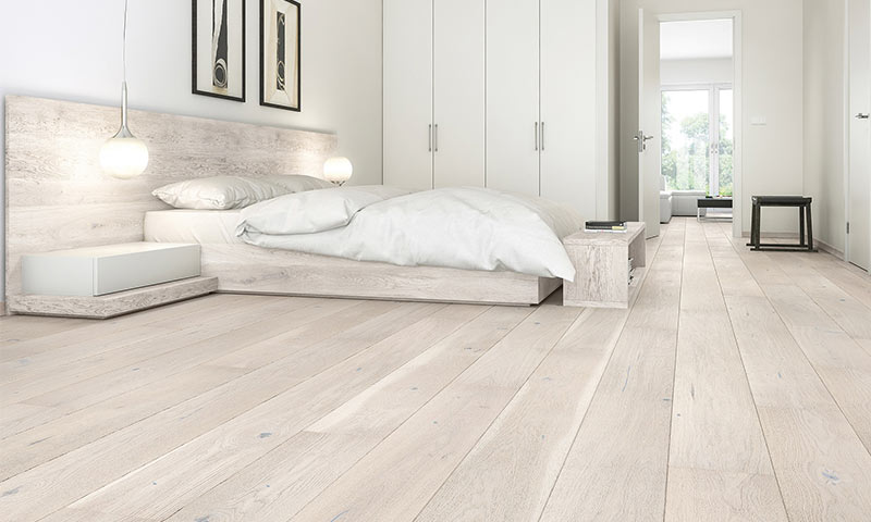 Lyst minimalistisk soverom med hvit dobbeltseng, hengende lamper, lyst tre og garderobe.