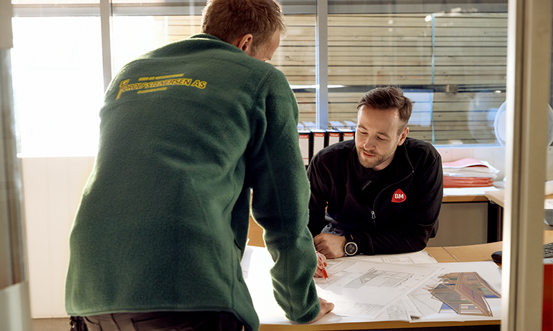 to menn som lener seg over et bord med papirer