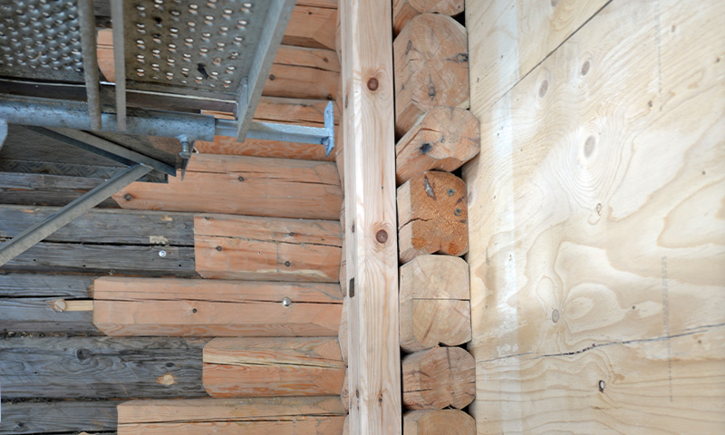 Gråslitt tre til venstre, oransje tømmerstokker midt, lyst kryssfiner høyre, metallstillas