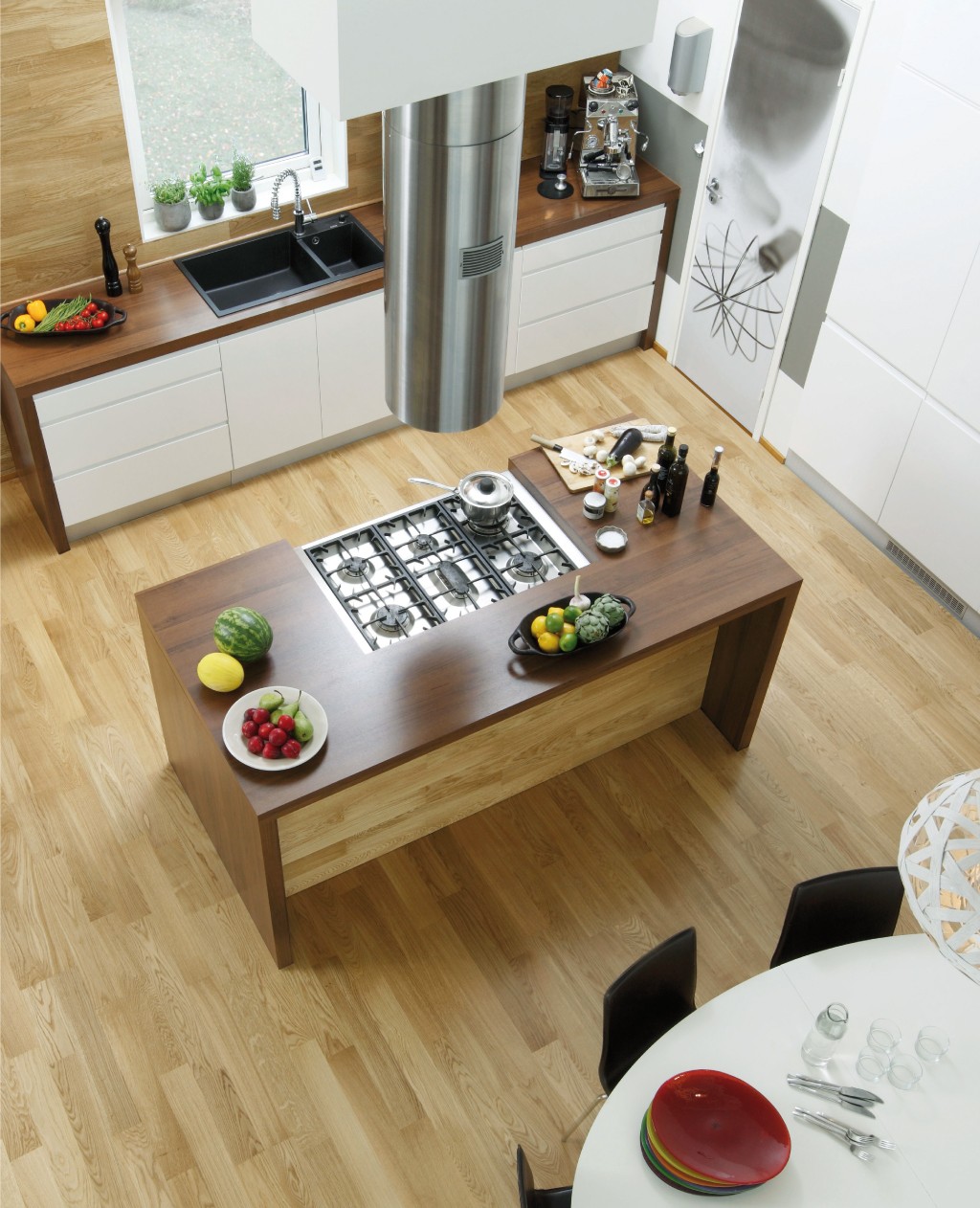 Moderne kjøkken ovenfra: eikegulv, mørk trefjøl med gasskomfyr, fruktfat, hvite skap.