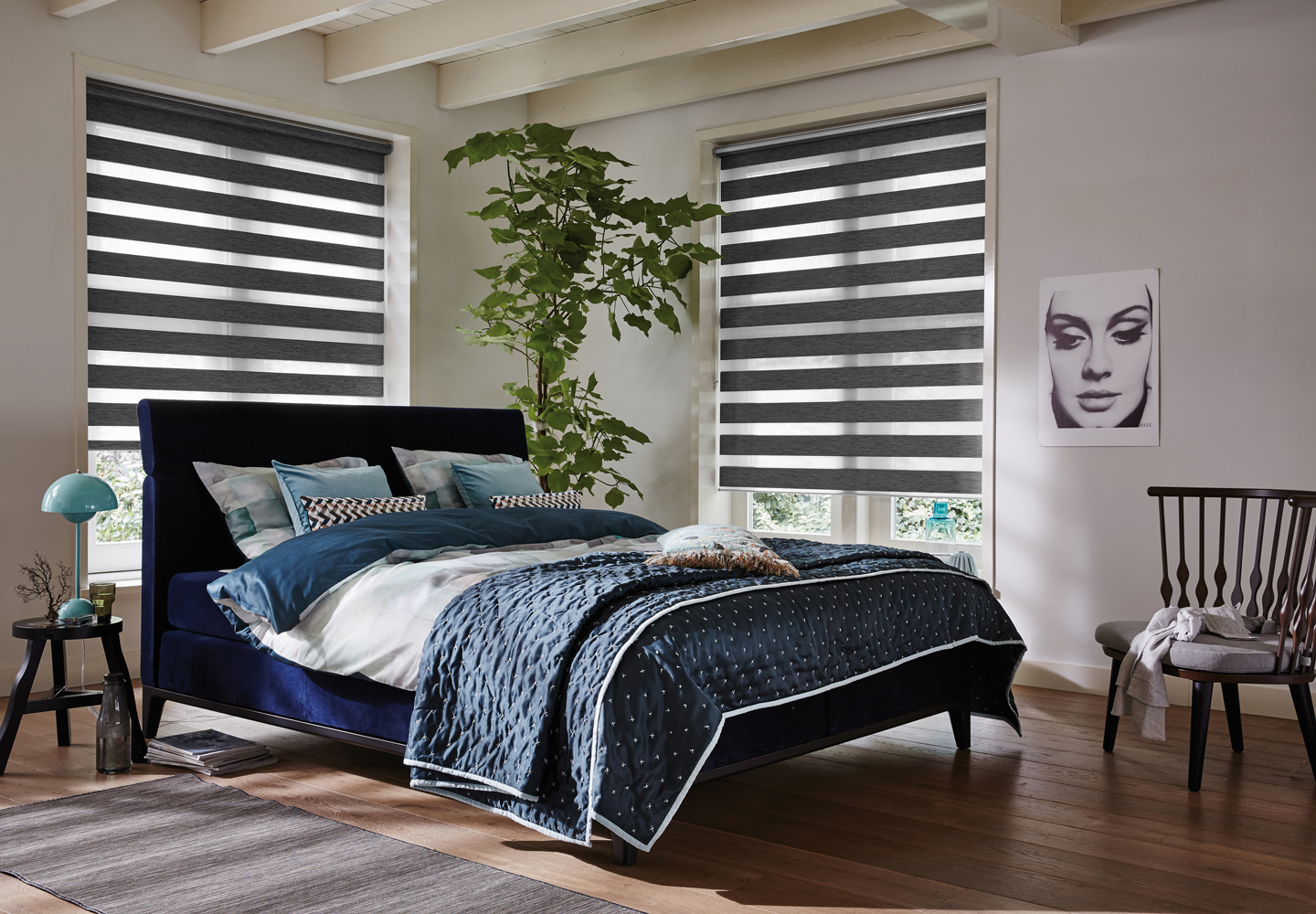 Moderne soverom med mørkeblå seng, stripete svarte-hvite rullegardiner, grønne planter