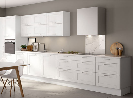 Lysegrått kjøkken med hvite skap, marmorplate bak komfyr, trebord med hvite stoler.