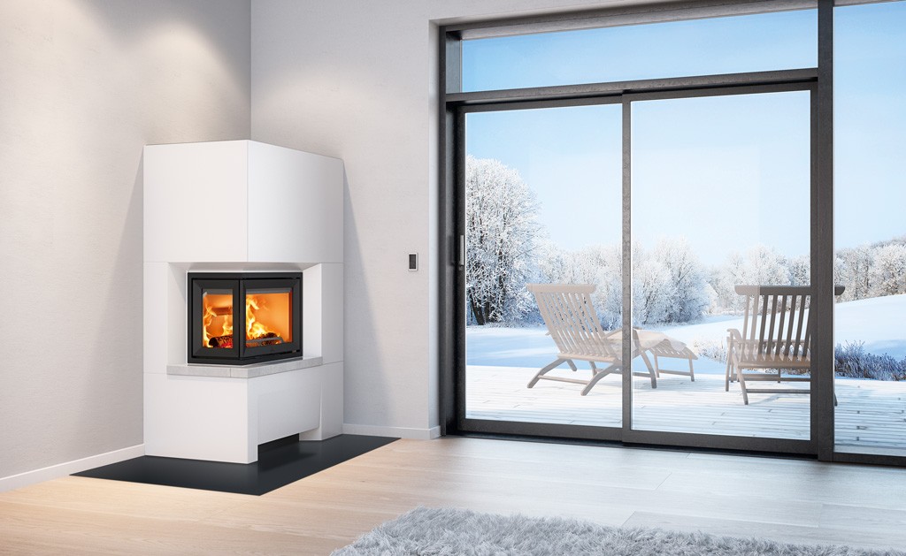 Moderne hvit hjørnepeis med oransje flammer og glassterrassedør ut mot snødekt landskap