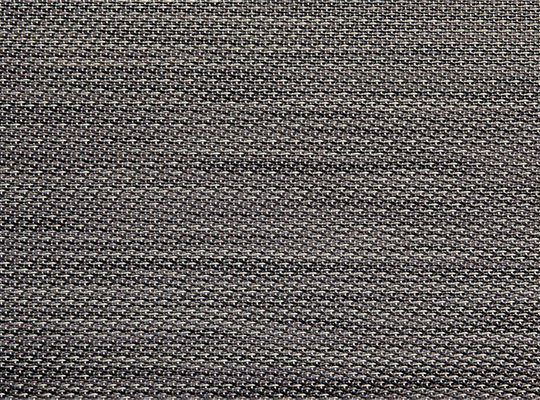 Nærbilde av gråsvart vevet tekstil med tett repeterende mønster.