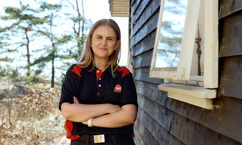 Jente med armene i kryss utendørs ved gammelt vindu