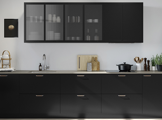 Moderne kjøkken med matte sorte skap, ribbet glass, lys benkeplate, vask, skjærebrett og potteplante